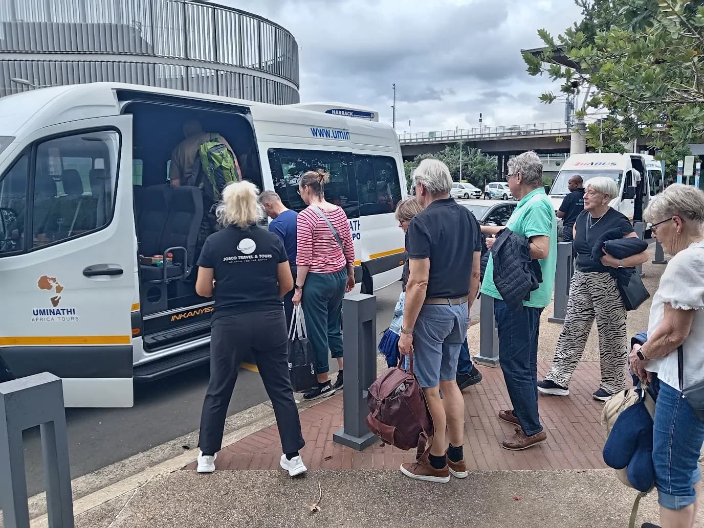 Guests loading luggage into Khondlo Tours shuttle vans at an airport